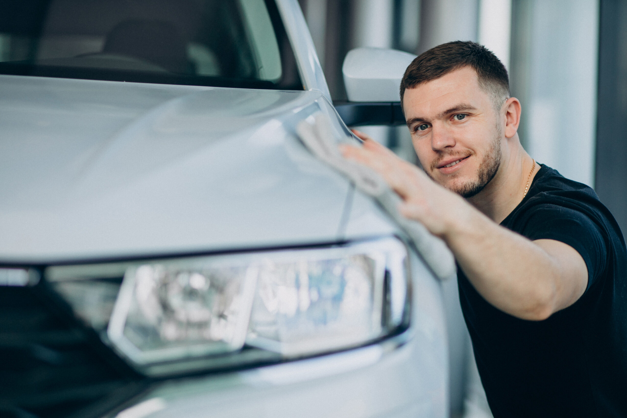 Young man polishing his car with rag